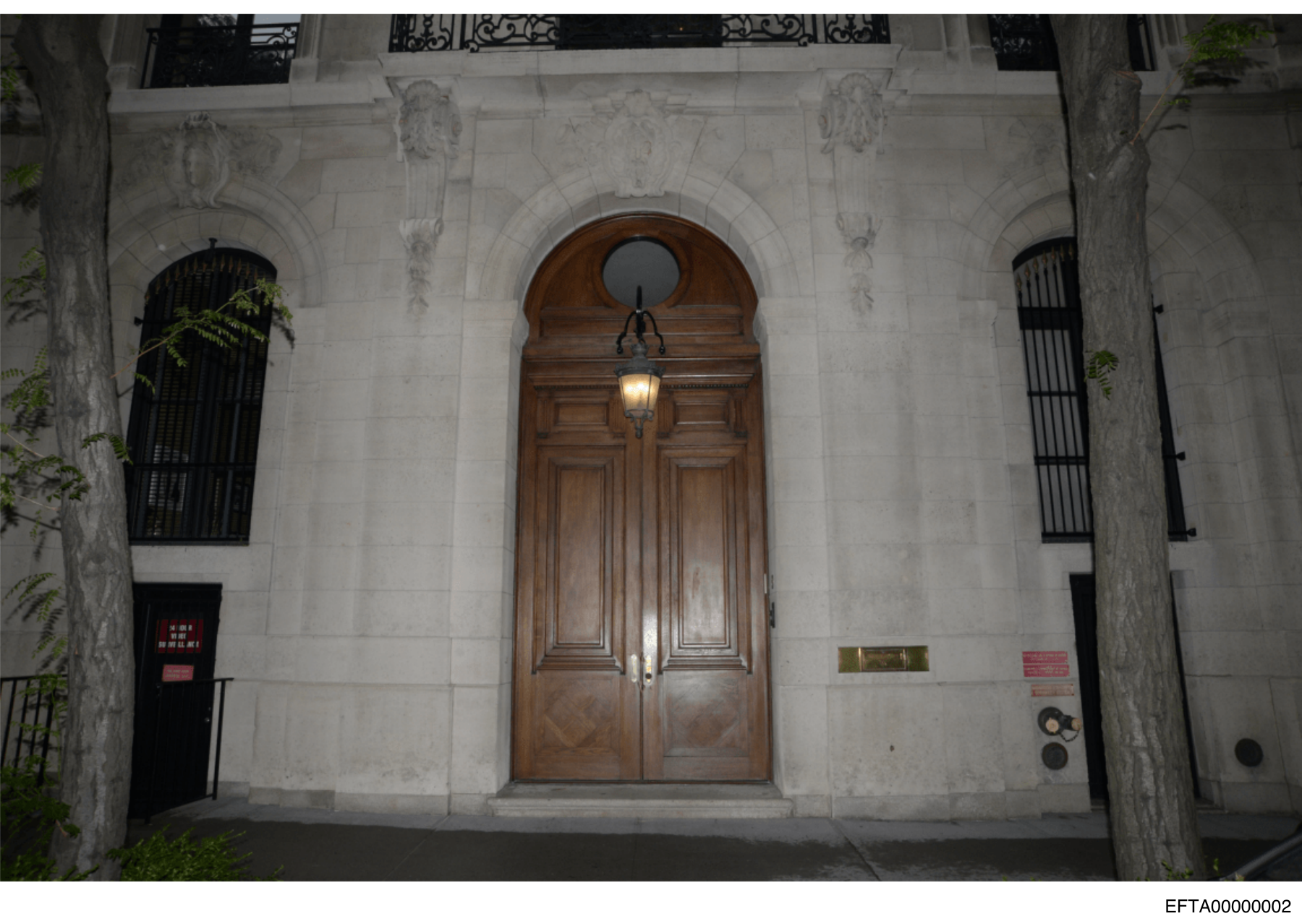 Released photograph of a stone building entrance with wooden double doors and a hanging lantern, labeled EFTA00000002