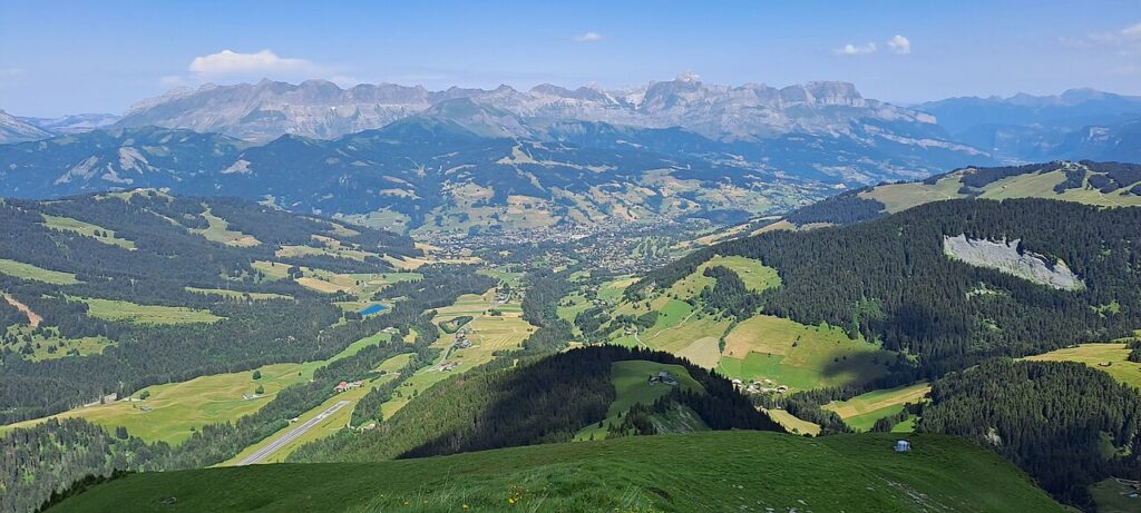 Megève village in a green Alpine valley beneath the Aravis mountains.
